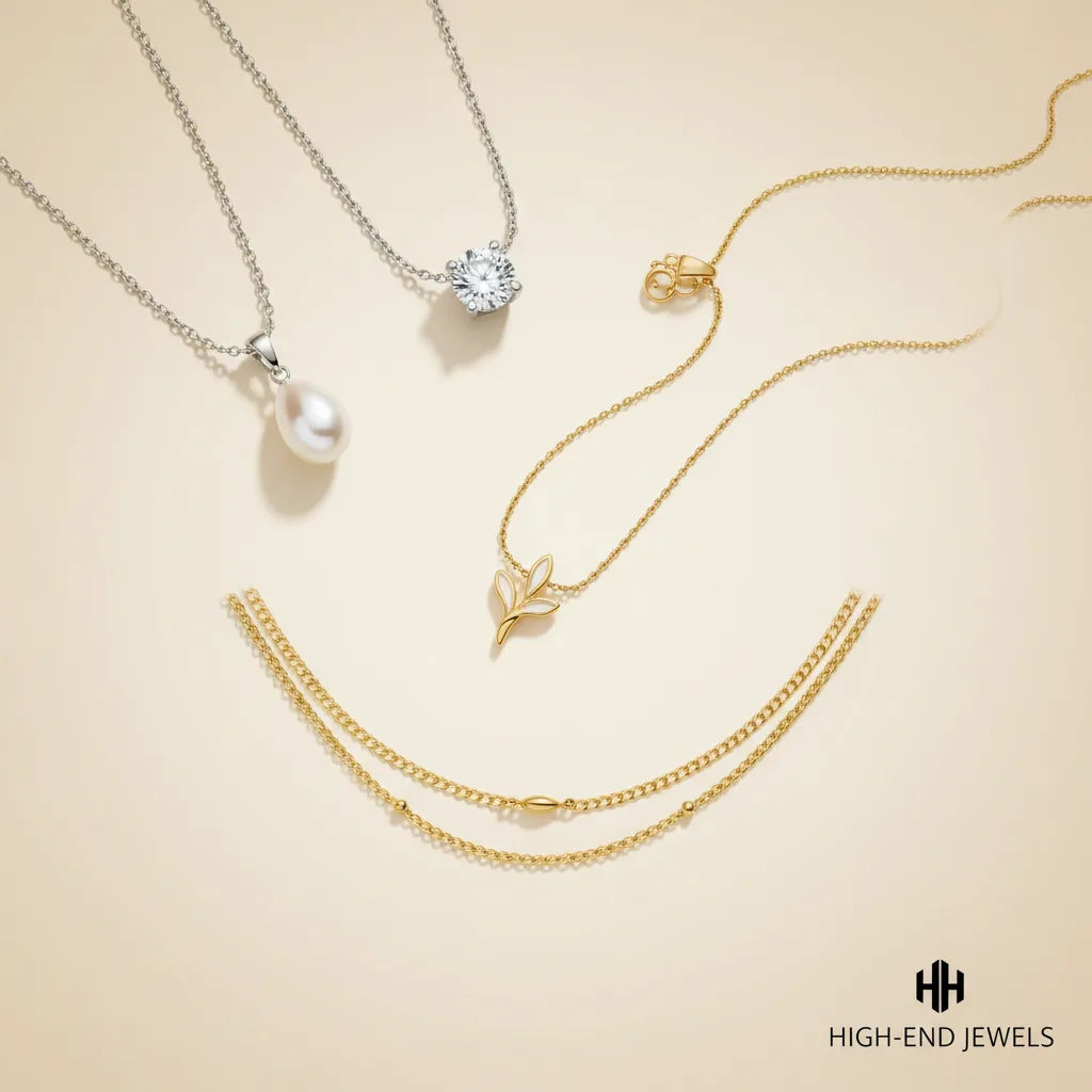 Four delicate jewelry pieces arranged on a warm cream background: a silver chain necklace with a white pearl pendant, a silver small leaf pendant, and a double-layered gold chain necklace.