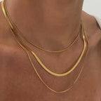 Close-up of a person wearing a Gold Plated Three-Layer Snake Chain Necklace featuring three delicate, layered gold plated snake chains resting elegantly on the neck and collarbone.