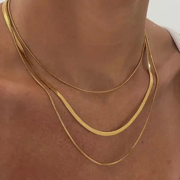 Close-up of a person wearing a Gold Plated Three-Layer Snake Chain Necklace featuring three delicate, layered gold plated snake chains resting elegantly on the neck and collarbone.