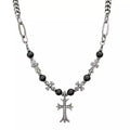 Necklace with black beads and silver cross pendants on a white background