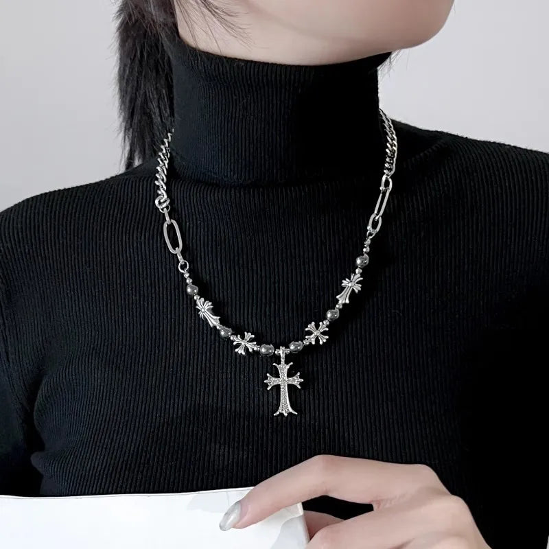 Person wearing a black turtleneck with a silver necklace featuring a cross pendant.
