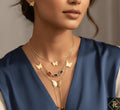Woman wearing a gold butterfly necklace with a blue top