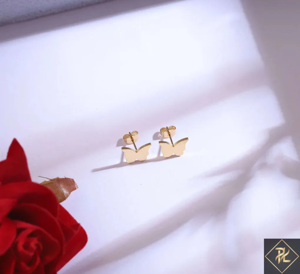 Gold boat-shaped earrings on a white fabric background with a red rose.