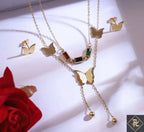 Gold butterfly necklace with gemstones on a white surface with a red rose.