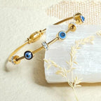 Gold bracelet with blue evil eye charms on a white stone surface
