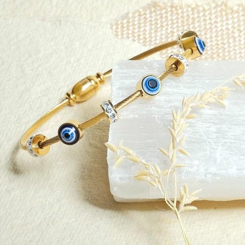 Gold bracelet with blue evil eye charms on a white stone surface