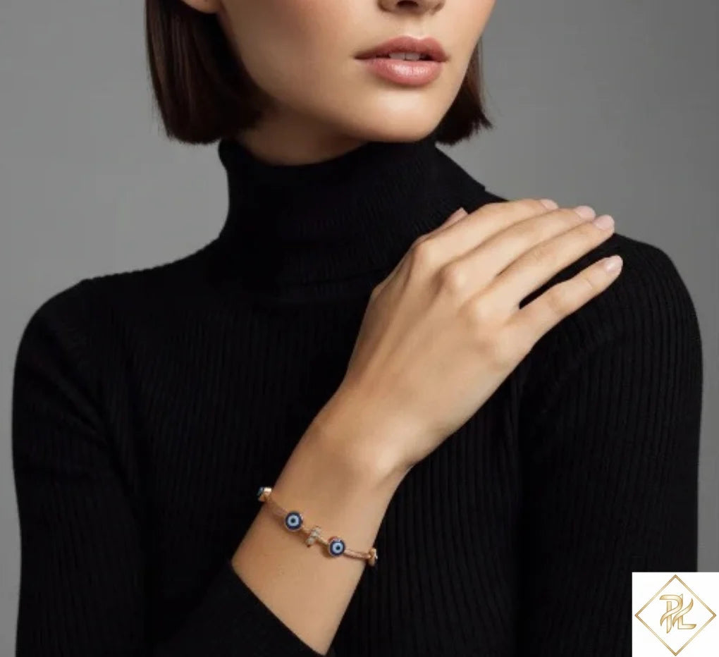 Woman wearing a black turtleneck and bracelet with eye design on a gray background