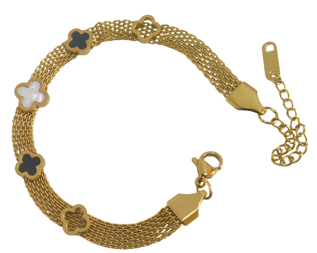 A gold-tone mesh bracelet with five clover-shaped links, three of which are filled with black enamel and one with a white inlay, photographed on a light off-white background.