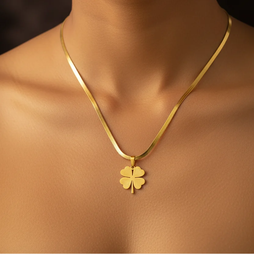 A gold four-leaf clover pendant necklace displayed on a model's neck and upper chest.