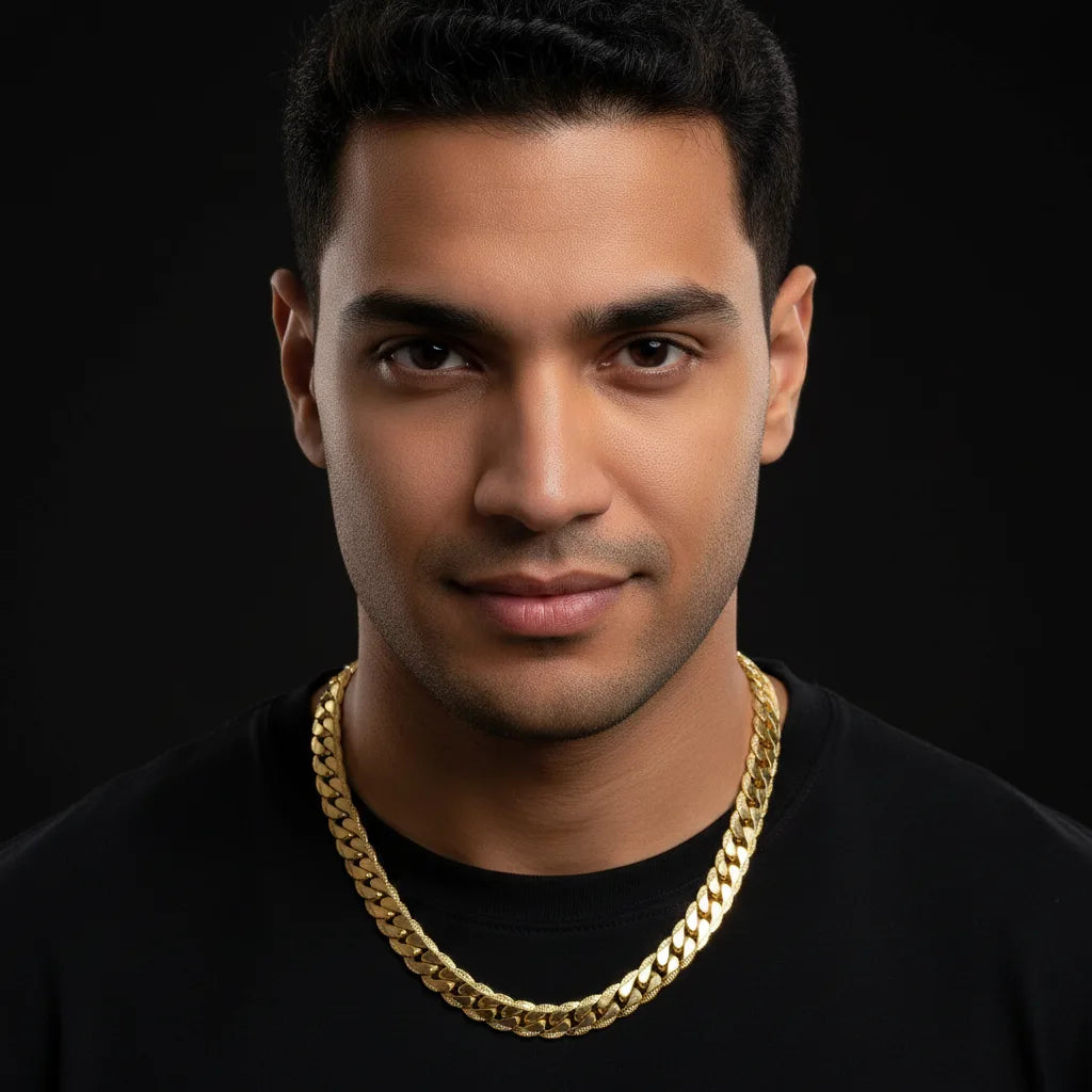 A man wearing a thick gold Cuban link chain necklace over a black t-shirt, photographed against a solid black background.