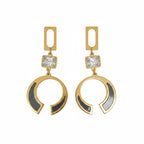 A pair of gold-tone statement dangle earrings with a rectangular cutout top, a clear square crystal, and a large open crescent-shaped drop featuring black inlay details, shown on a plain white background.