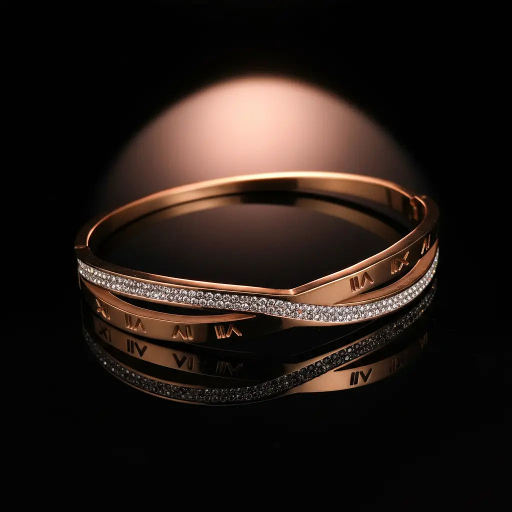 A rose gold bangle bracelet with a row of clear pavé-set stones and Roman numeral engravings, displayed on a reflective black surface against a dark background.