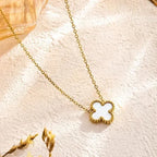 Gold necklace with a white pendant on a soft pink background