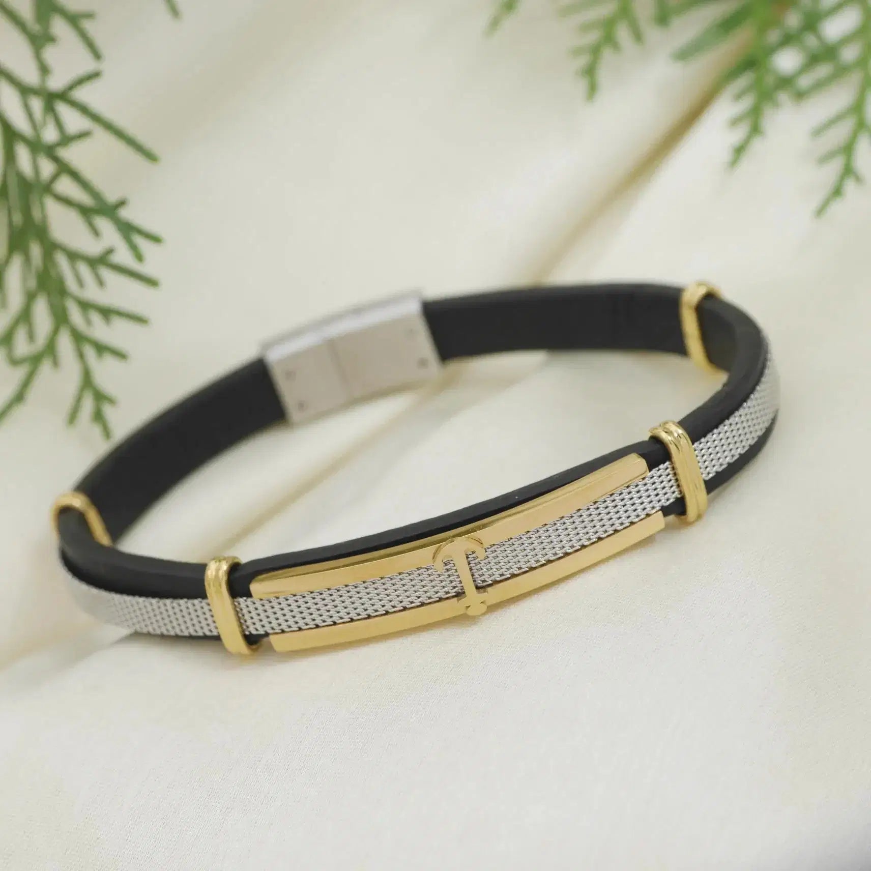Bracelet with black strap, gold accents, and silver clasp on a light background