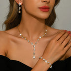 Woman wearing a gold and pearl necklace and bracelet with red lipstick.