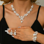 Woman wearing a set of silver jewelry including necklace, earrings, and bracelet.