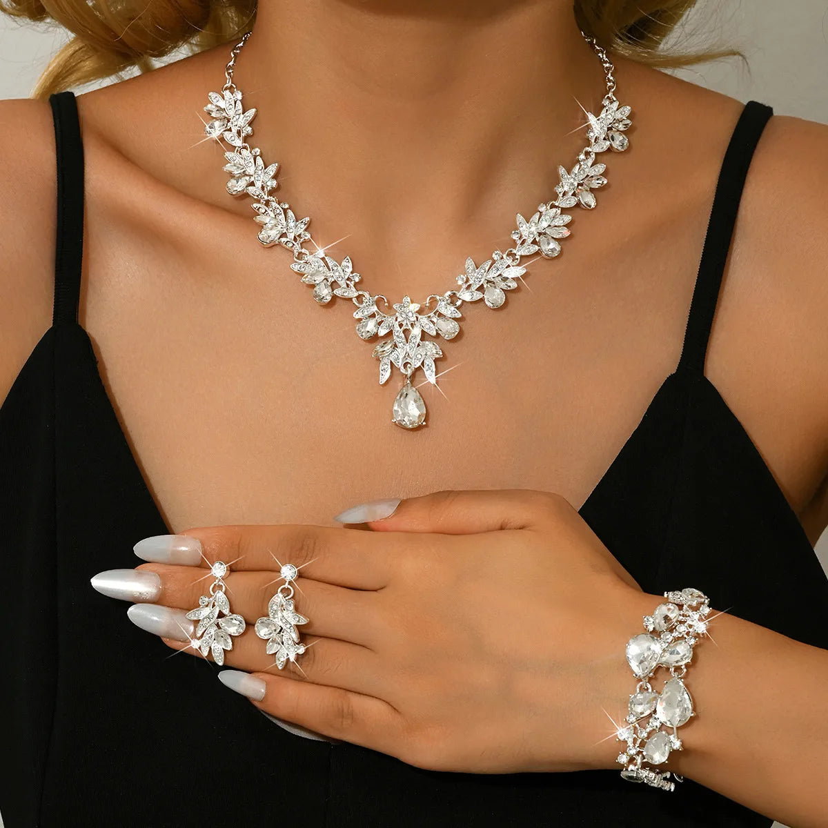 Woman wearing a set of silver jewelry including necklace, earrings, and bracelet.