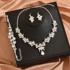 Silver necklace and earrings set on a black jewelry box with a pink fabric background