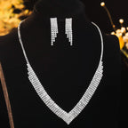 Silver necklace and earrings on a black mannequin with blurred floral background