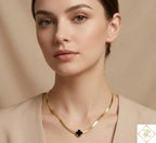 Close-up of a woman wearing a Lucky Clover Snake Chain Necklace featuring a gold snake chain with a black clover-shaped pendant, styled with a neutral-toned outfit.