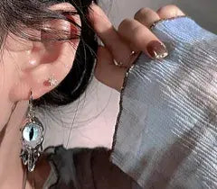 Close-up of an ear with a silver earring and a hand holding a light blue fabric.