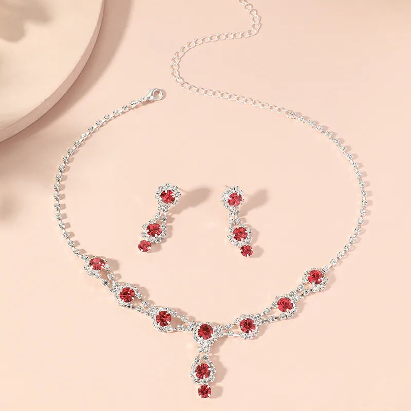Jewelry set with necklace and earrings featuring red gemstones on a beige background