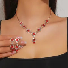 Red gemstone necklace, bracelet, and ring set on a black top