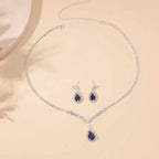 Jewelry set with necklace and earrings featuring blue gemstones on a beige background