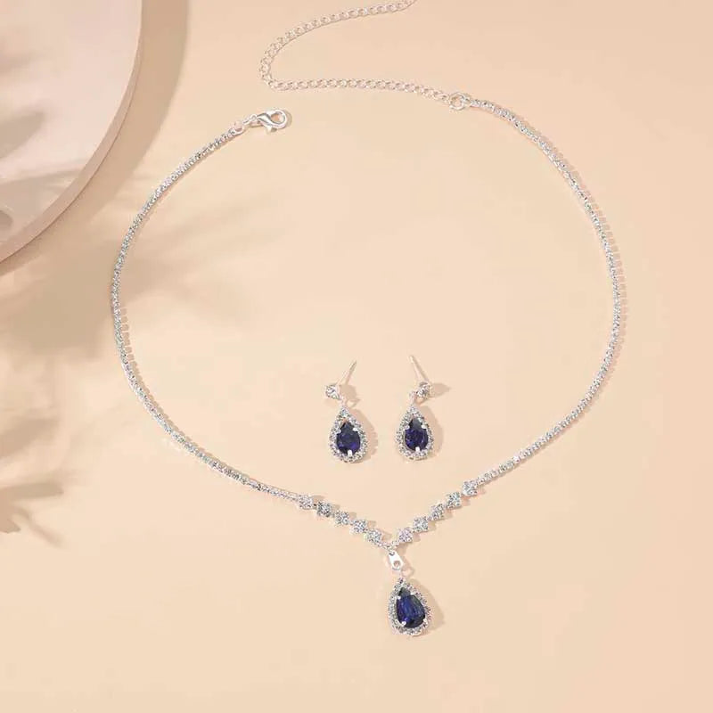 Jewelry set with necklace and earrings featuring blue gemstones on a beige background