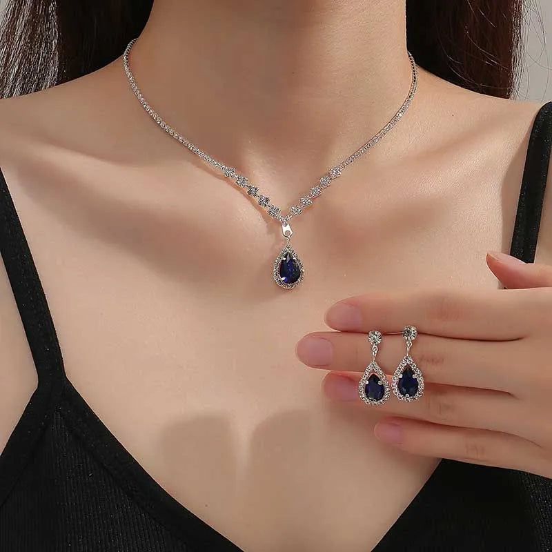 Jewelry set with necklace and earrings featuring blue gemstones on a model.