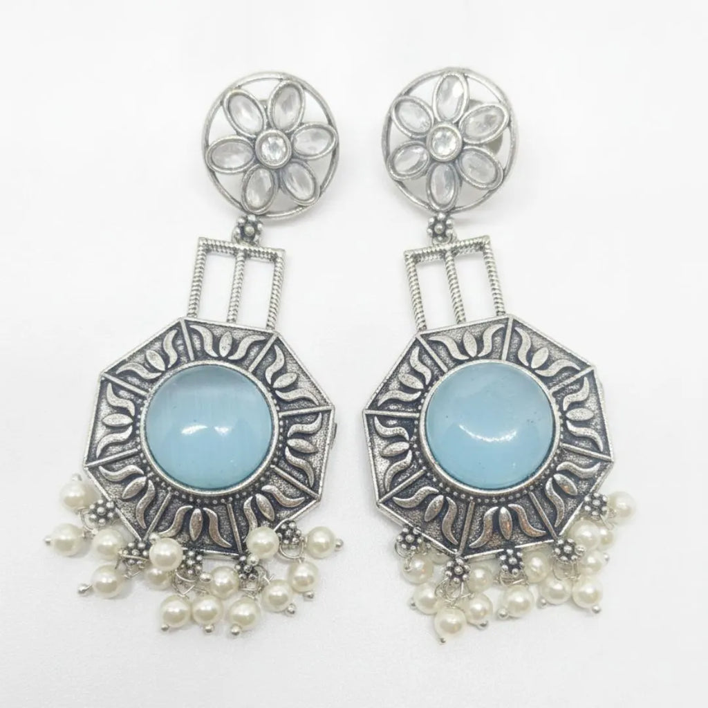 A pair of silver-toned statement dangle earrings with oval light blue center stones and dangling pearl-like beads, shown on a plain white background.