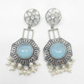 A pair of silver-toned statement dangle earrings with oval light blue center stones and dangling pearl-like beads, shown on a plain white background.
