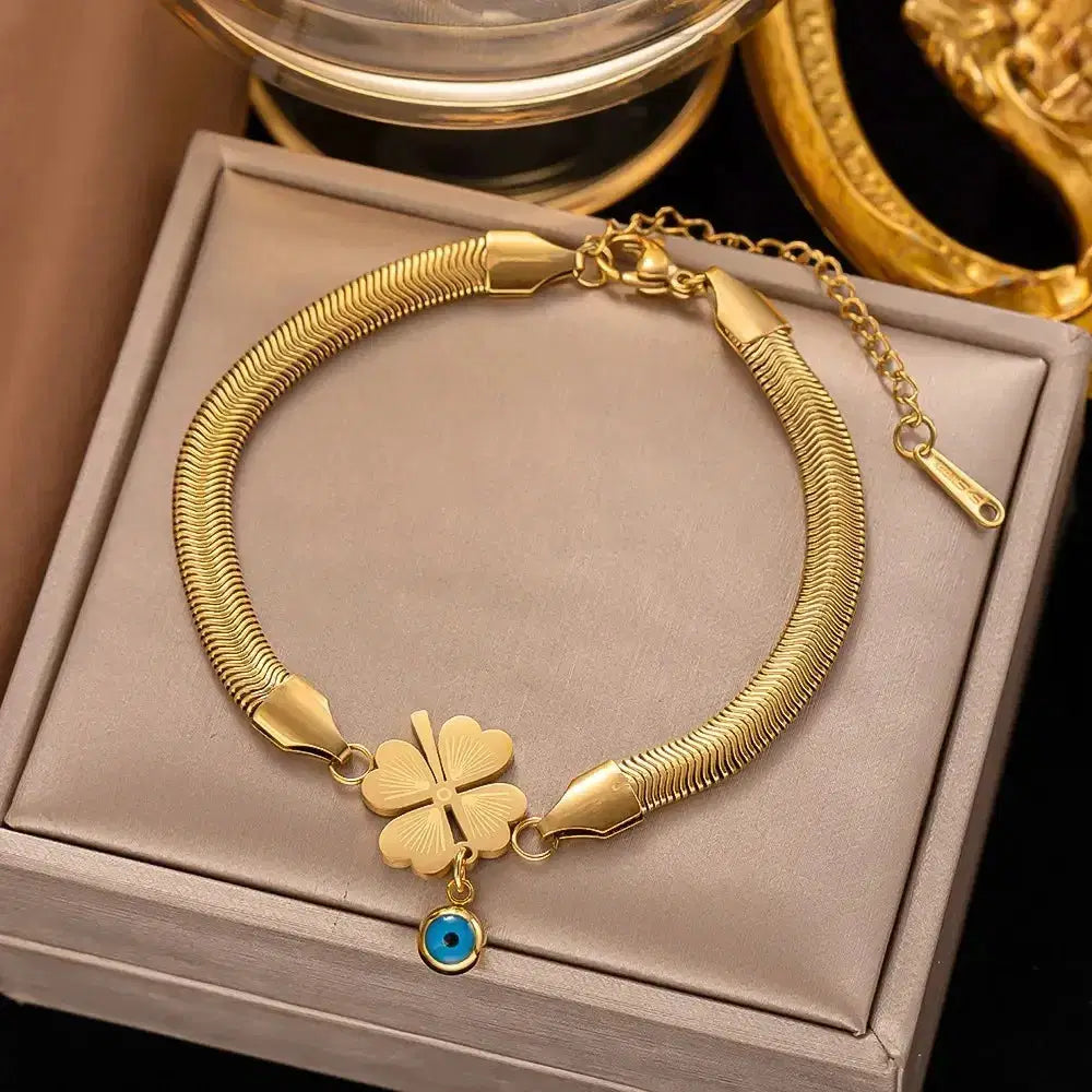 Evil's Eye Leaf Charm Snake Chain Bracelet in gold tone with a four-leaf clover charm and a small blue evil eye pendant, a stylish luxury fashion jewelry accessory.