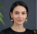 Woman wearing gold earrings with a dark background
