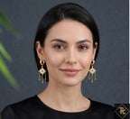 Woman wearing gold earrings with a dark background
