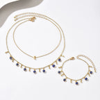 Gold necklace and bracelet set with blue eye charms on a white background