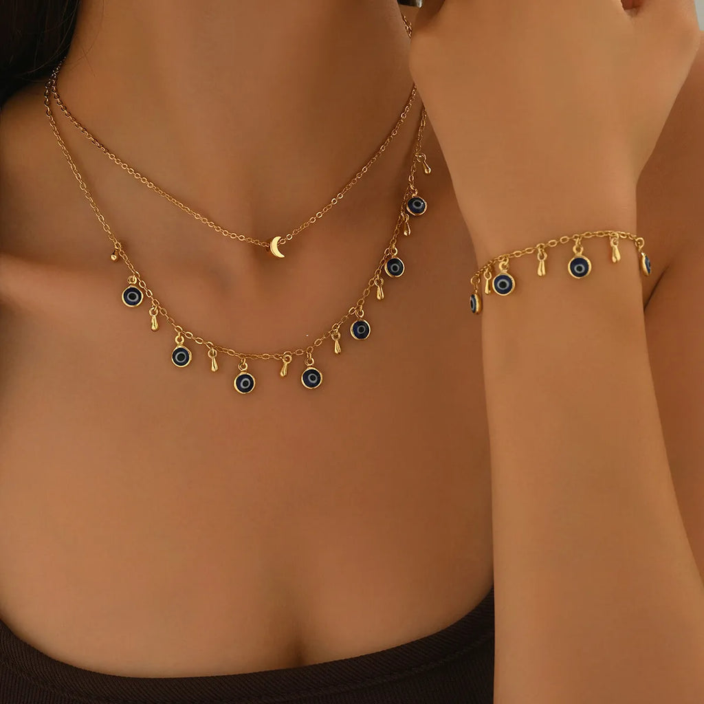 Gold necklace and bracelet with blue beads on a person's neck and wrist.