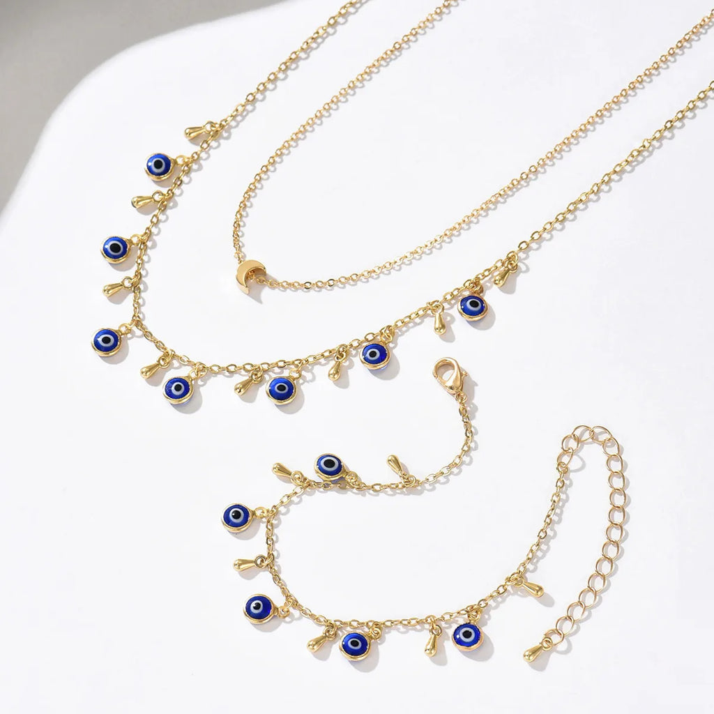 Gold necklaces with blue evil eye charms on a white surface