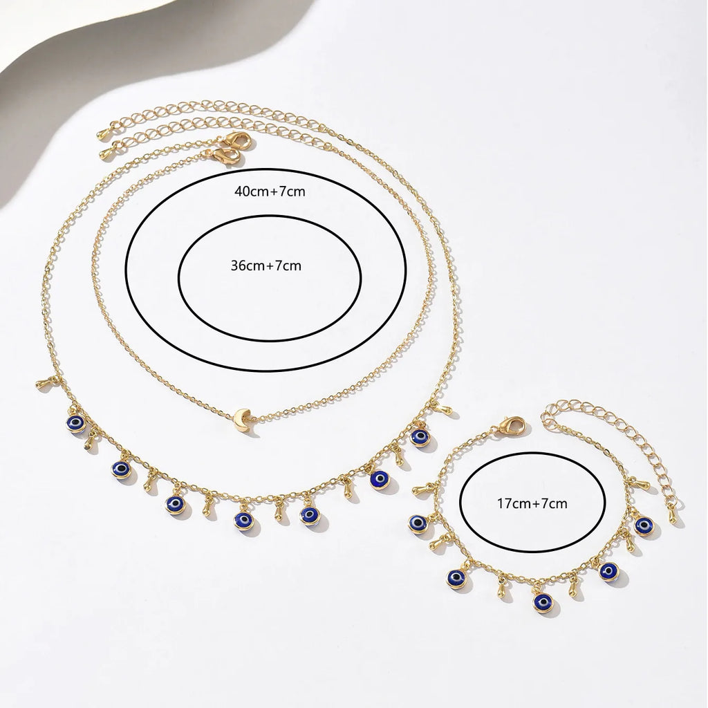Gold necklace with blue eye charms and measurements on a white background