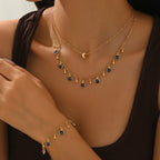 Gold necklace with blue gemstones on a person wearing a black top.
