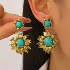 Gold earrings with turquoise stones worn by a person