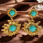 Gold earrings with turquoise stones on a brown surface