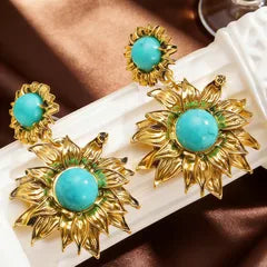 Gold earrings with turquoise stones on a white surface