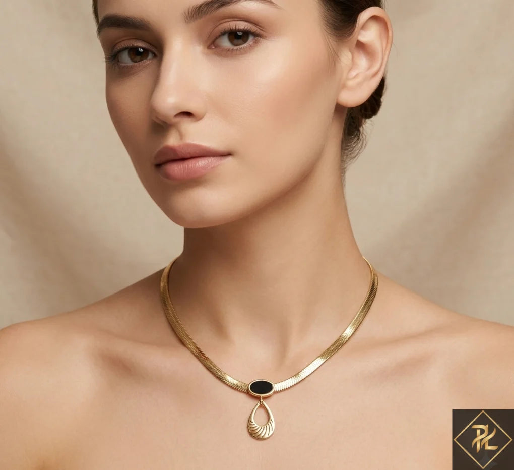 Woman wearing a gold necklace with a black pendant against a beige background
