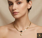 Woman wearing a gold necklace with a black pendant against a beige background