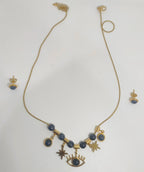 Gold necklace with blue beads and charms on a white background