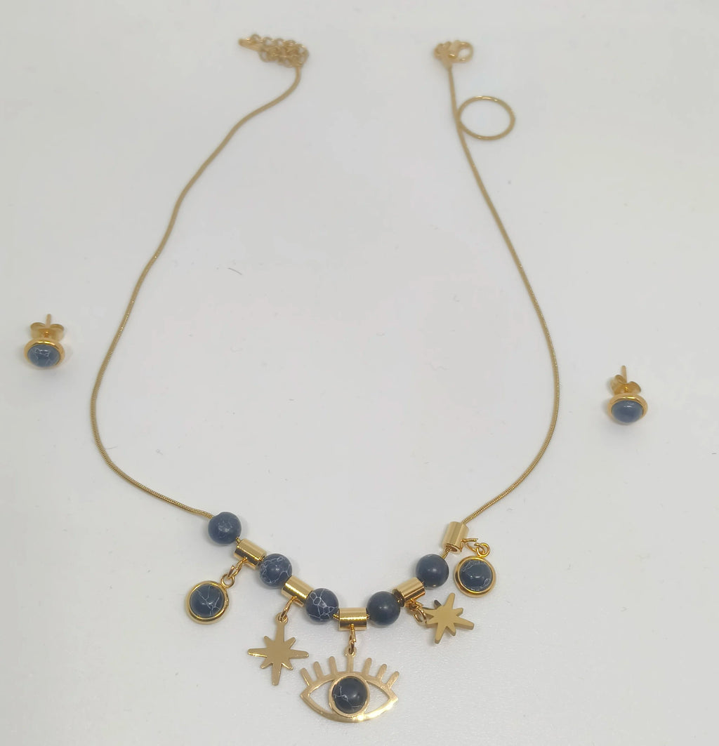 Gold necklace with blue beads and star, eye, and moon charms on a white background