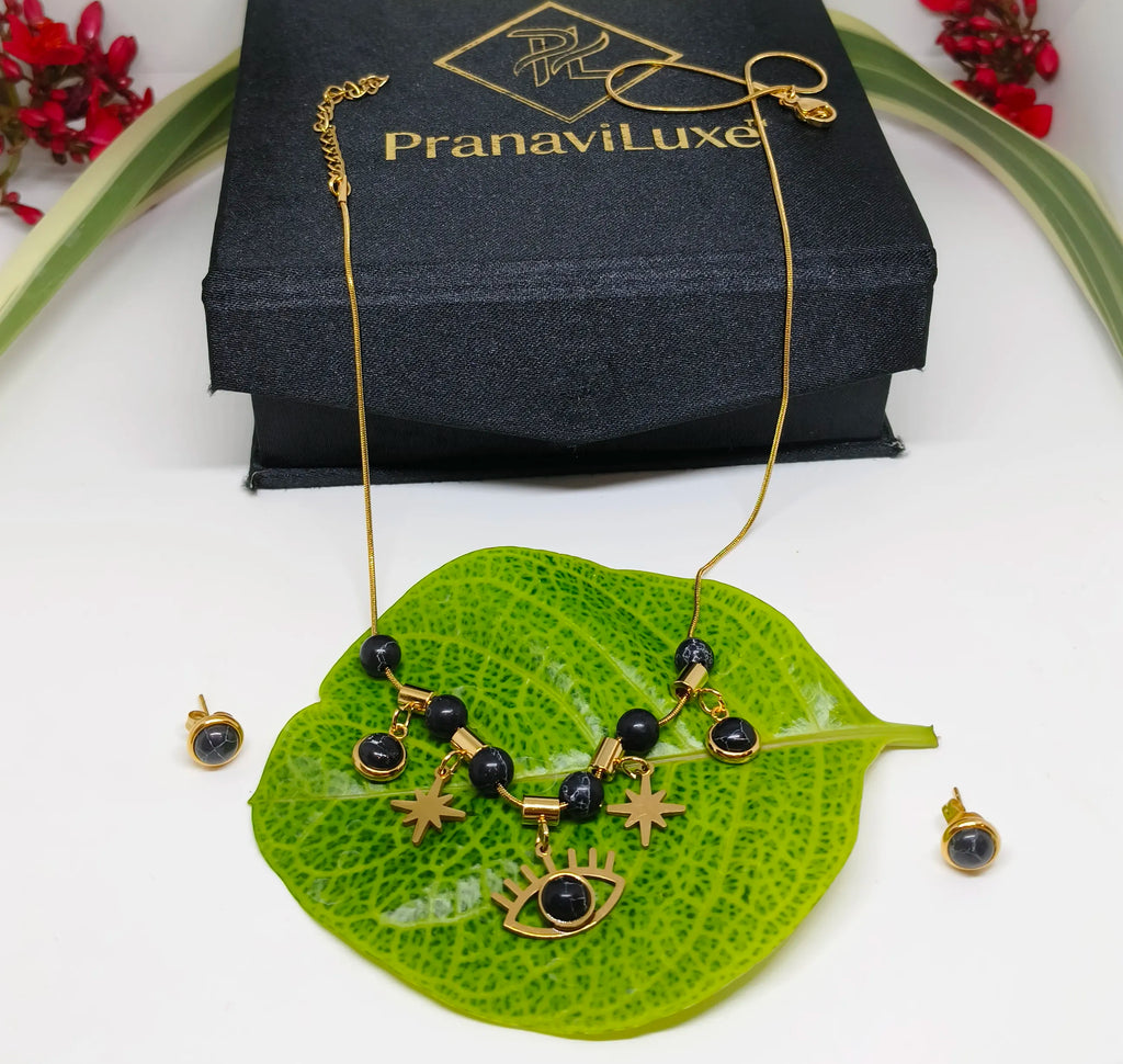 Gold necklace with black beads on a green leaf, PranaviLuxe box in the background