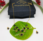 Gold necklace with black beads on a green leaf, PranaviLuxe box in the background