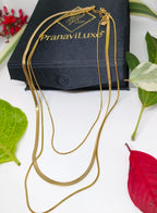 Gold necklace on a PranaviLuxe branded box with leaves and flowers around